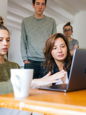 Woman In Green Top Using Macbook Beside Group Of People